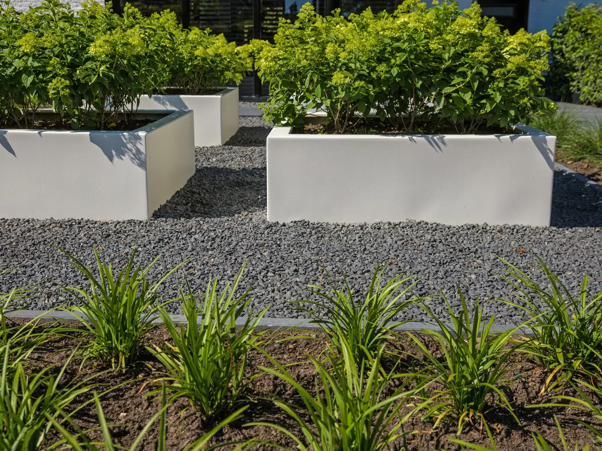 Grindvlak met plantvakken en siergrassen in een onderhoudsvriendelijke tuin